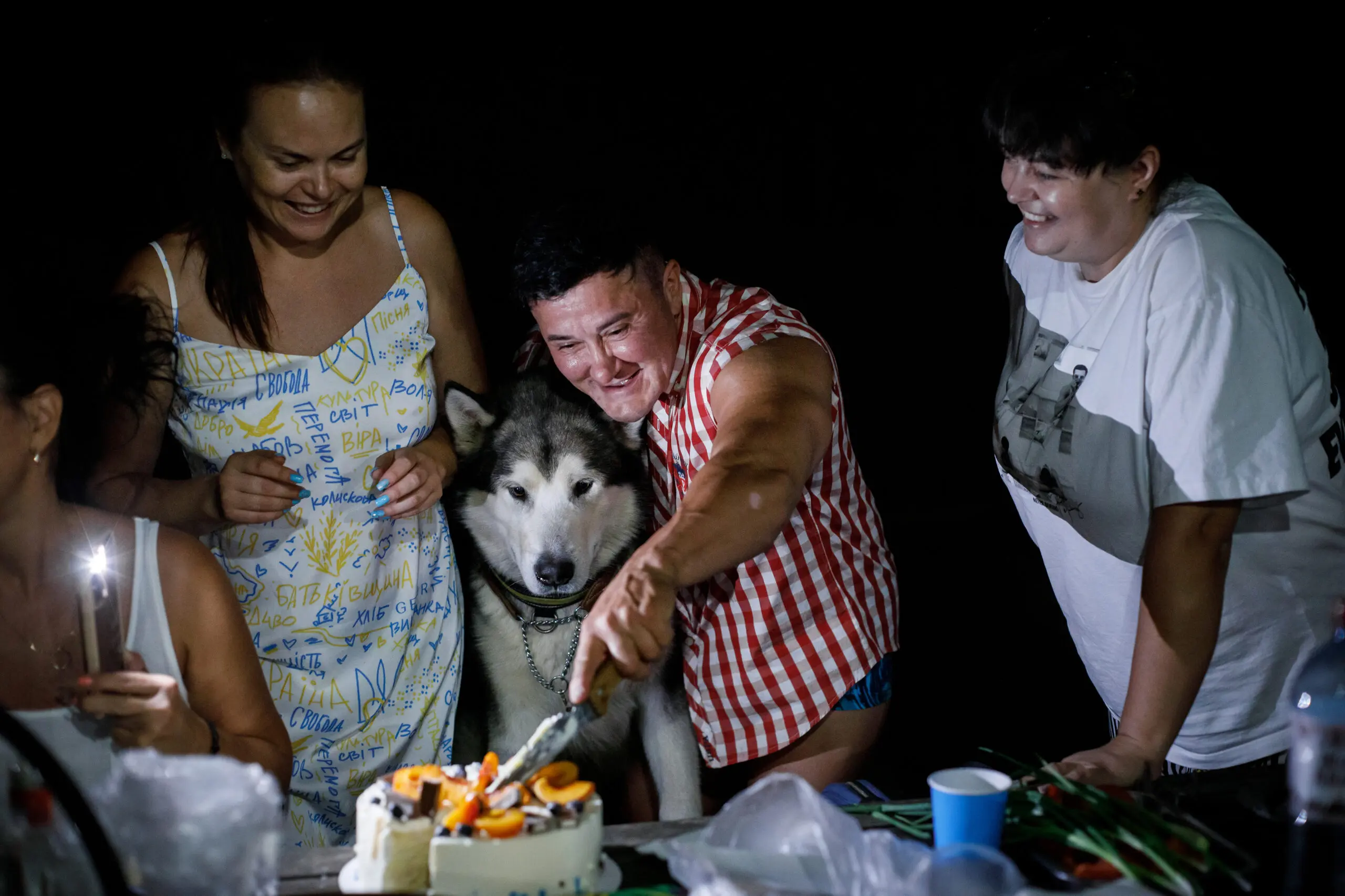 Anna Kurkurina cuts a cake while celebrating her birthday surrounded by friends, neighbors, and animals.