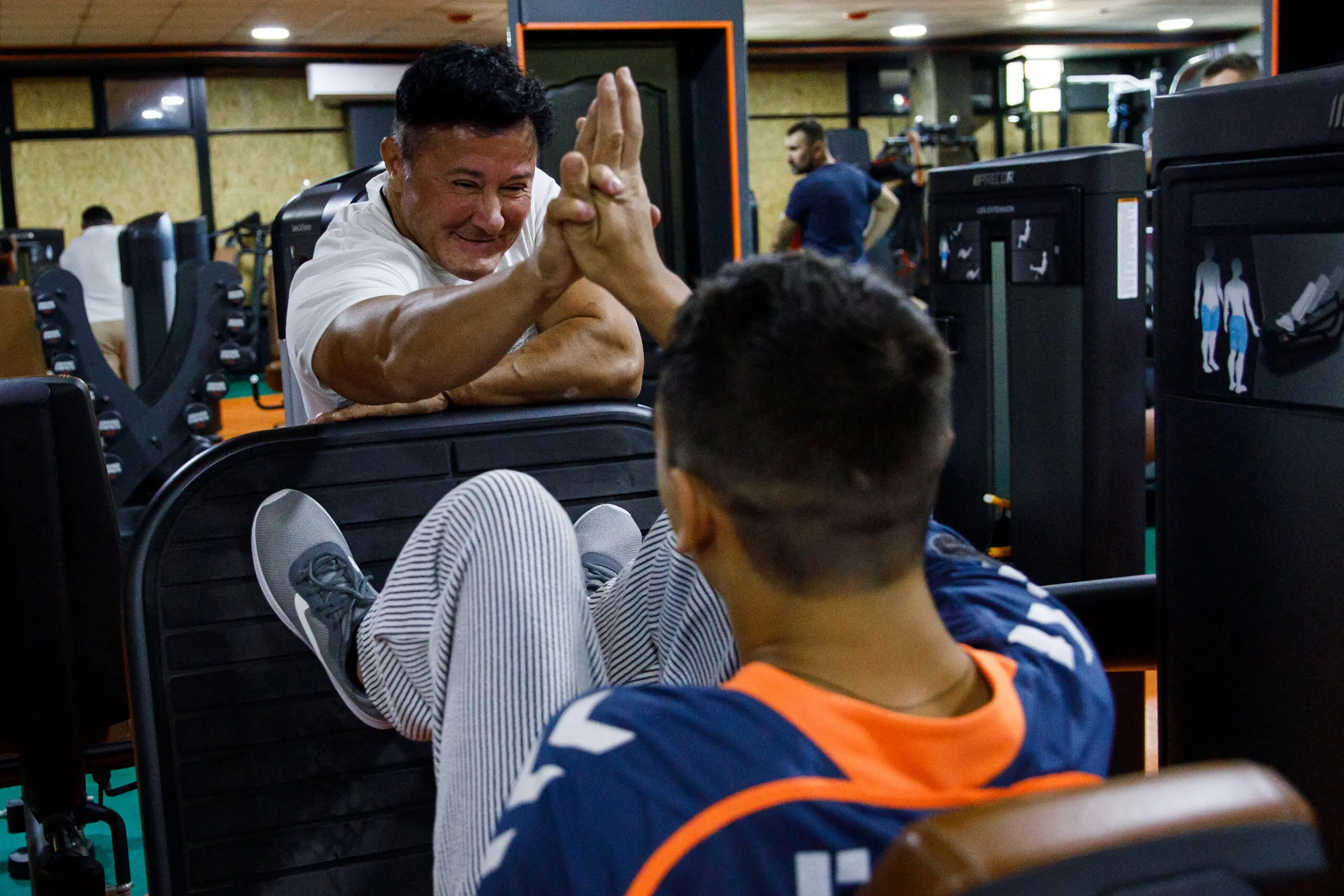 Anna Kurkurina high-fives Dmitry Zakrevsky, a young man with cerebral palsy, after a successful leg press.