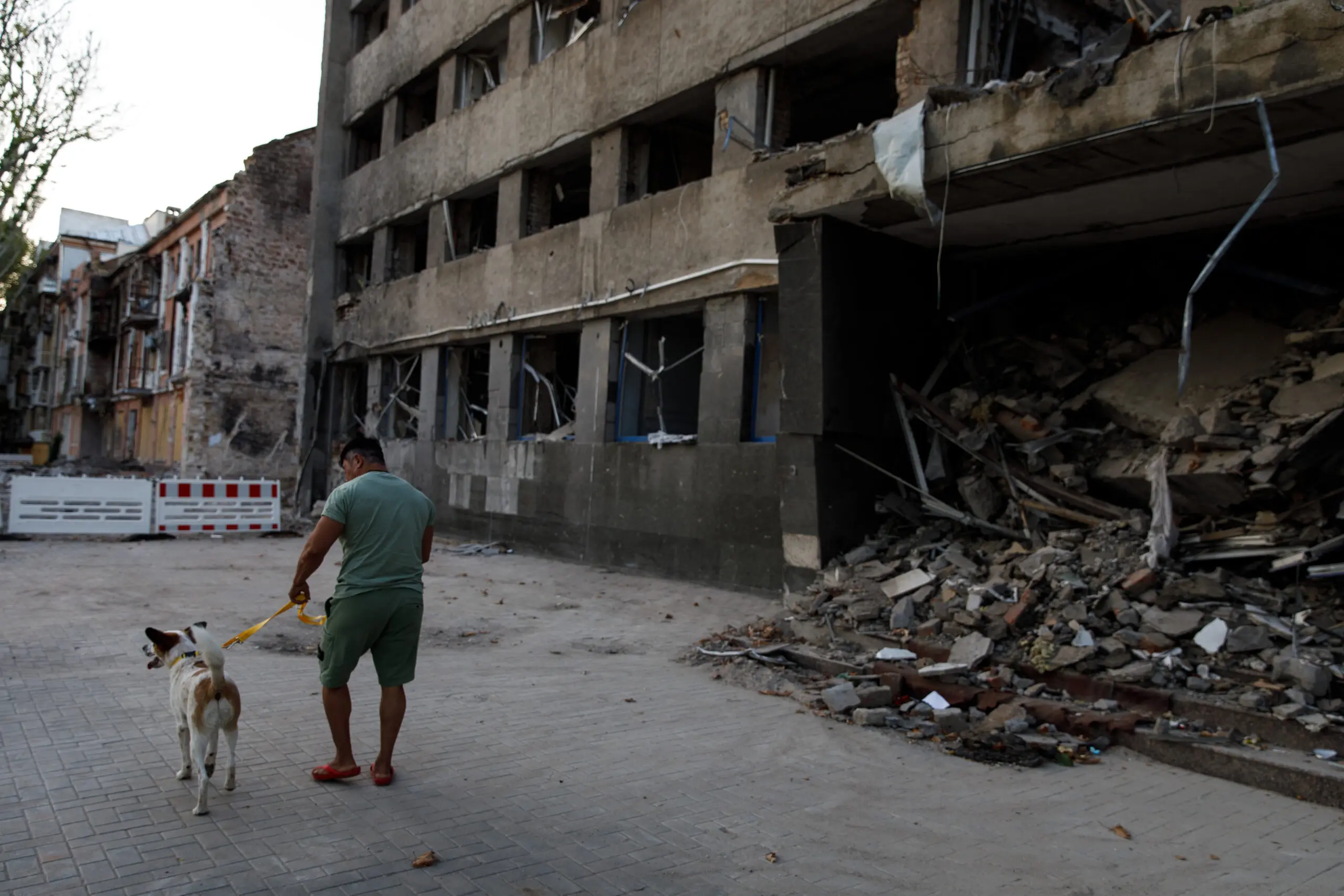 Anna and her dog Jack walk past a building destroyed by a Russian airstrike in downtown Mykolaiv, Ukraine.